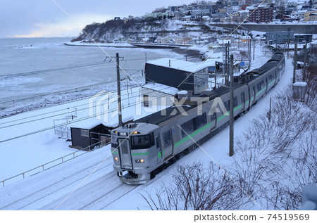 Regular train on the Hakodate Main Line that goes beside Higashi Otaru Beach in winter 74519569