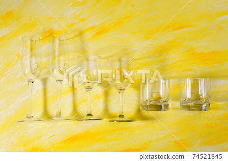 Variety of drinking empty glasses on yellow background with hard shadows and sun glare. sober concept. the view from the top Variety of drinking empty glasses on yellow background with hard shadows and sun glare. sober concept. the view from the top 74521845