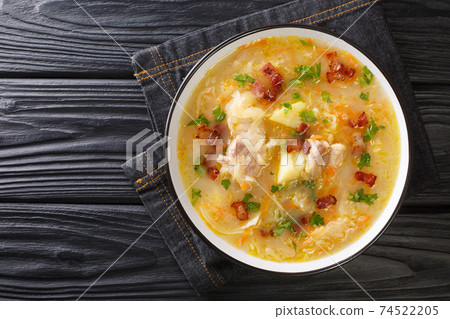 Delicious Polish sauerkraut soup with vegetables and ribs and bacon close-up in a plate. horizontal top view 74522205