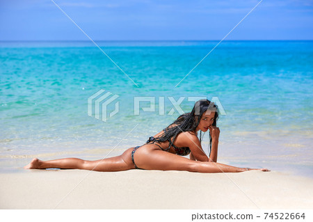 Sexy girl sitting in a splits at the sand inthe tropical beach Sexy girl sitting in a splits at the sand inthe tropical beach 74522664