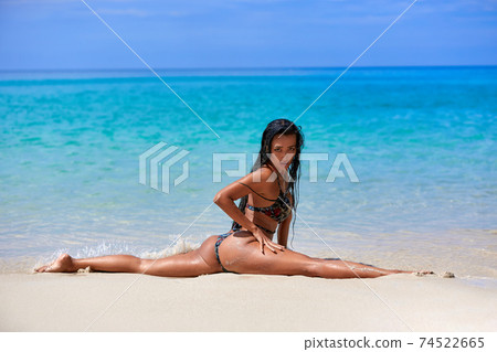 Sexy girl sitting in a splits at the sand inthe tropical beach Sexy girl sitting in a splits at the sand inthe tropical beach 74522665