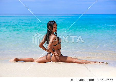 Sexy girl sitting in a splits at the sand inthe tropical beach Sexy girl sitting in a splits at the sand inthe tropical beach 74522666