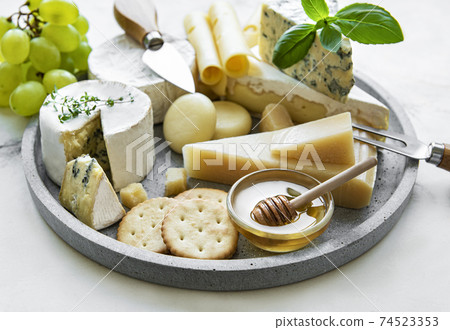 Various types of cheese, grapes and honey 74523353