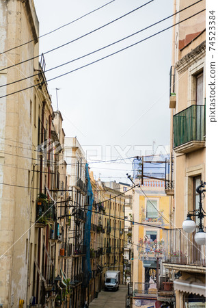 The streets of Tarragona, a suburb of Barcelona, Spain, apartments lined up on both sides of a narrow path The streets of Tarragona, a suburb of Barcelona, Spain, apartments lined up on both sides of a narrow path 74523384
