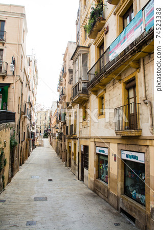 The streets of Tarragona, a suburb of Barcelona, Spain, apartments lined up on both sides of a narrow path The streets of Tarragona, a suburb of Barcelona, Spain, apartments lined up on both sides of a narrow path 74523388