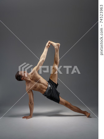 Athletic yoga doing stretching exercise in studio Athletic yoga doing stretching exercise in studio 74523963