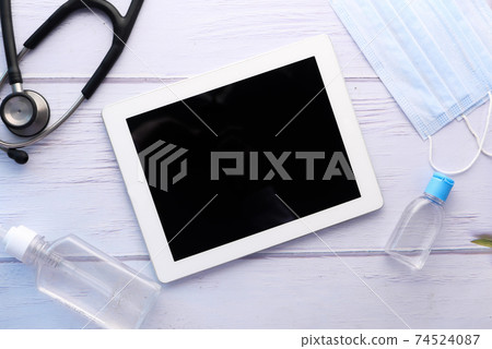 top view of digital tablet, hand sanitizer and stethoscope on table  74524087
