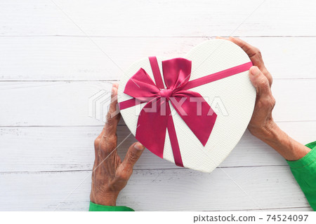 senior women hand on red color envelope and gift on table  74524097
