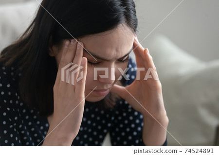 Young asian female sit alone rub temples having headache migraine 74524891