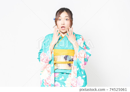 A woman in furisode standing in front of a white background and making a surprised pose 74525061