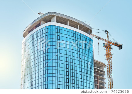 Crane near skyscraper with glass facade at construction site Crane near skyscraper with glass facade at construction site 74525656