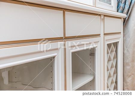 Classical style white showcase with glass doors and gilding closeup view 74528008