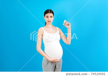 bottle of vitamin pills in pregnant woman's hand at colorful background with copy space. Healthcare concept 74529591