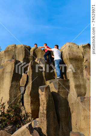 Tourists climb up the basalt pillars, tourist places of Ukraine, natural stone of the basalt rock. 74529971