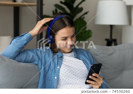 Female teenager in headset play mobile game satisfied with sound 74530260