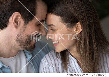 Young couple smiling leaning heads to one another whispering confessions 74530270