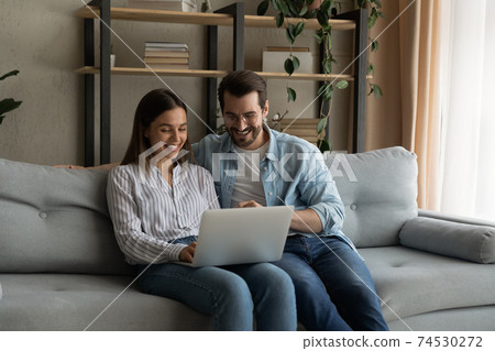 Young family couple sit by laptop discuss flat renovation options 74530272