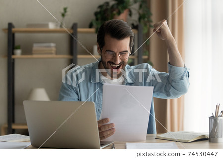 Motivated male student read official letter about admission to university Motivated male student read official letter about admission to university 74530447