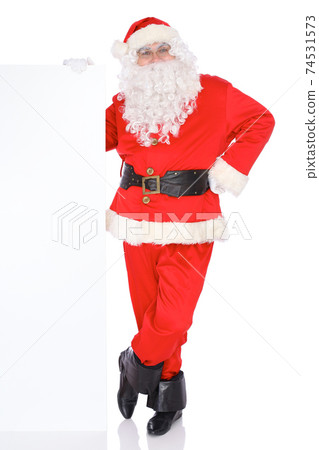 Santa Claus pointing on blank white wall, advertisement banner with copy space. Isolated on white background. Full length portrait 74531573