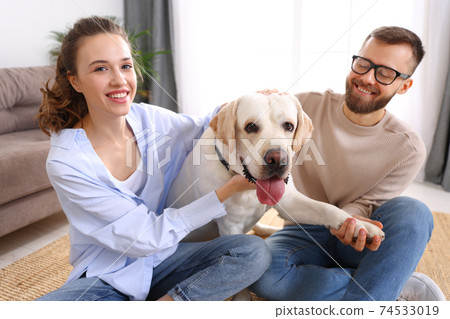 happy married couple playing with their favorite pet dog   at home 74533019