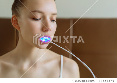 A young girl is engaged in home teeth whitening. 74534375