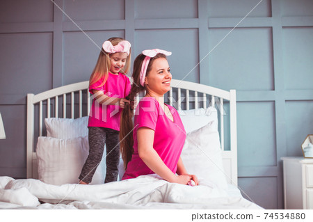 Little toddler girl combing her mother hair Little toddler girl combing her mother hair 74534880