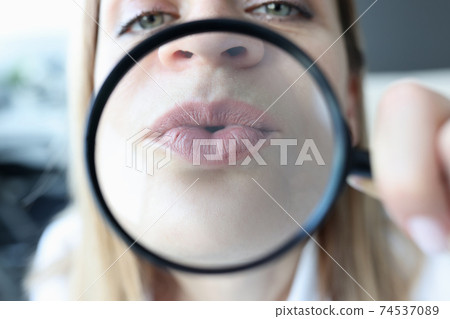 Woman shows her lips through magnifying glass 74537089
