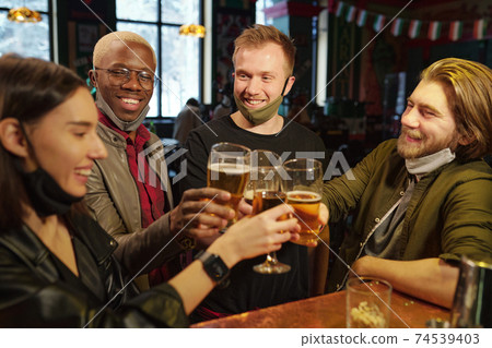 Group of young football fans clinking with glasses of beer over bar counter 74539403