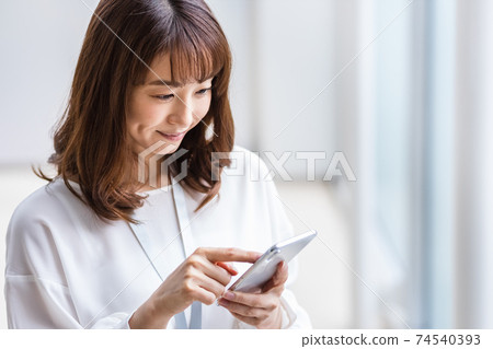 A woman who operates a smartphone with a smile A woman who operates a smartphone with a smile 74540393