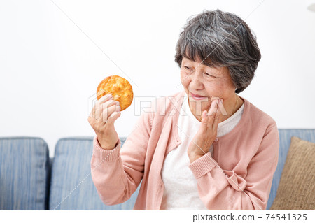 Senior woman eating rice crackers 74541325
