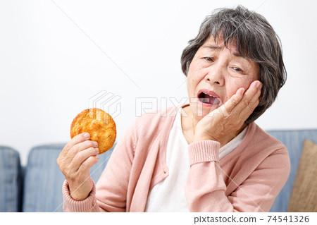 Senior woman eating rice crackers 74541326