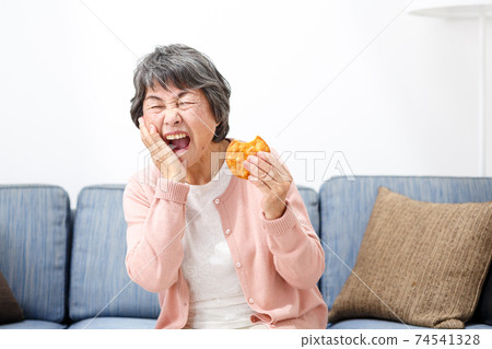 Senior woman eating rice crackers Senior woman eating rice crackers 74541328