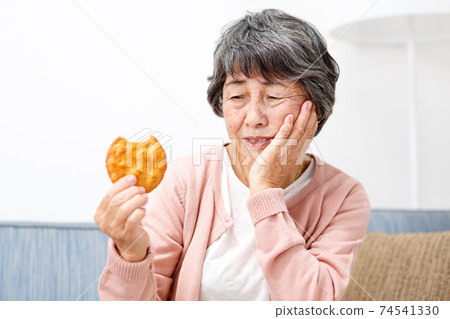 Senior woman eating rice crackers 74541330
