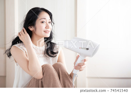 A woman using a hair dryer 74541540