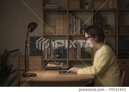 Night image of a young woman working on a laptop 74542441