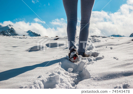 The legs of a woman in sporting winter shoes in deep snow. Blue sky The legs of a woman in sporting winter shoes in deep snow. Blue sky 74543478