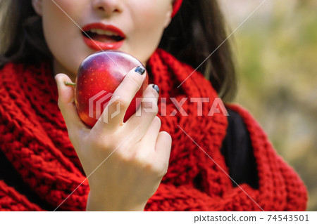 A young woman is eating a ripe red apple. The forbidden fruit. A young woman is eating a ripe red apple. The forbidden fruit. 74543501