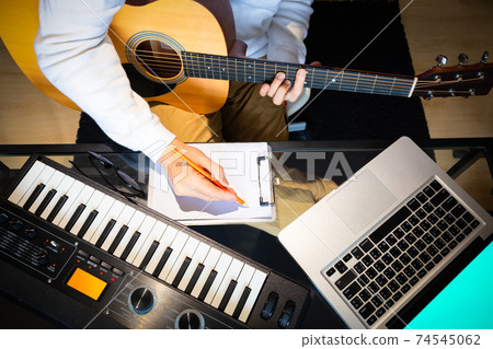 top view of male songwriter writing a song with laptop computer and keyboard on desk. songwriting concept top view of male songwriter writing a song with laptop computer and keyboard on desk. songwriting concept 74545062