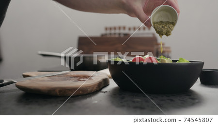 man pour dressing on salad on kitchen countertop man pour dressing on salad on kitchen countertop 74545807