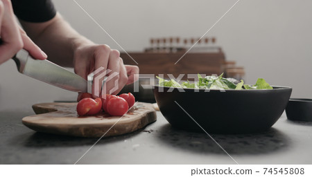 man cut cherry tomato for salad on kitchen countertop man cut cherry tomato for salad on kitchen countertop 74545808