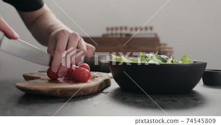 man cut cherry tomato for salad on kitchen countertop man cut cherry tomato for salad on kitchen countertop 74545809