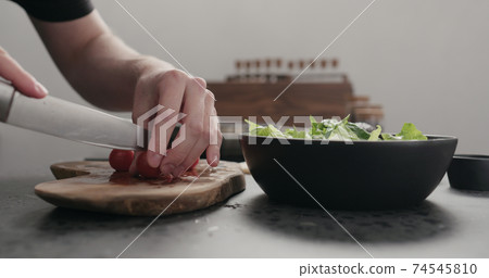 man cut cherry tomato for salad on kitchen countertop man cut cherry tomato for salad on kitchen countertop 74545810