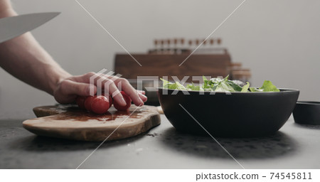 man cut cherry tomato for salad on kitchen countertop 74545811
