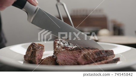 man slicing new york steak on white plate 74545842