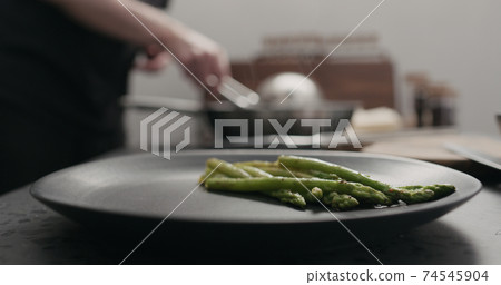 put roasted asparagus on black plate 74545904