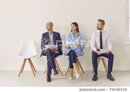Group of business people coworkers sitting on chairs, looking aside and and waiting for meeting Group of business people coworkers sitting on chairs, looking aside and and waiting for meeting 74546558