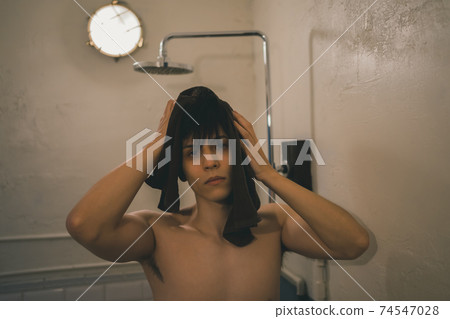 A man wiping his hair with a towel after a shower 74547028