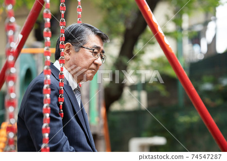 A businessman twilight on a swing in the park A businessman twilight on a swing in the park 74547287