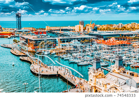 BARCELONA, SPAIN - SEPTEMBER 03: View of the embankment of Barcelona and the bridge "Sea Rambla" in September 03, 2014 in Barcelona, Catallonia, Spain. The most popular place to walk for tourists. BARCELONA, SPAIN - SEPTEMBER 03: View of the embankment of Barcelona and the bridge "Sea Rambla" in September 03, 2014 in Barcelona, Catallonia, Spain. The most popular place to walk for tourists. 74548333