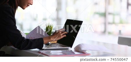 Cropped shot of internal revenue service inspector using laptop and checking financial document in office. Cropped shot of internal revenue service inspector using laptop and checking financial document in office. 74550047